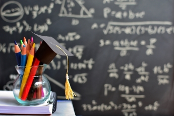 A jar of pens in front of a blackboard