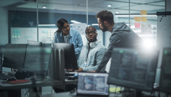 Three people crowded around a computer