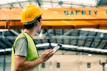 An individual standing in font of a large machine which reads safety