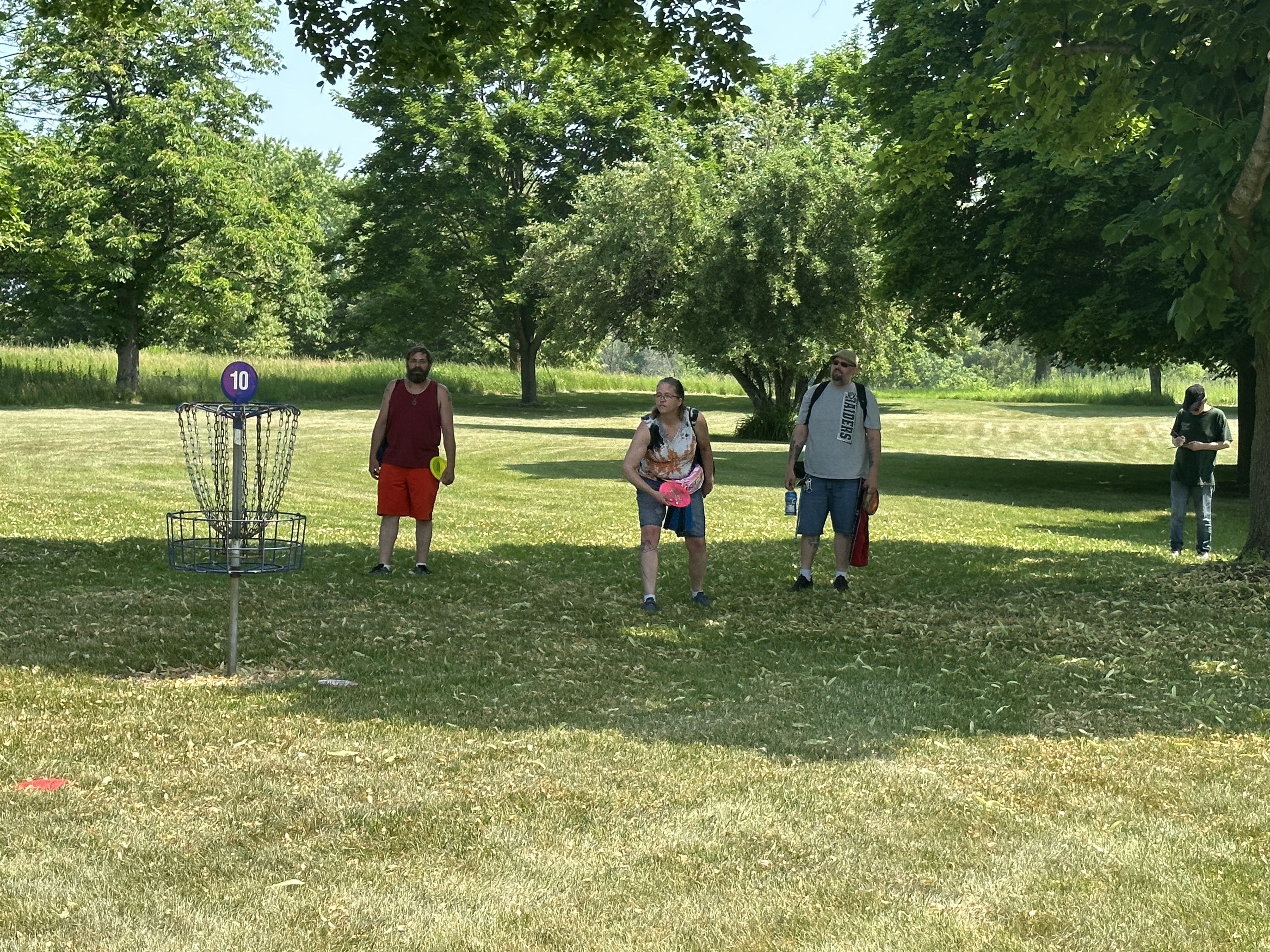 Three individuals playing disc golf